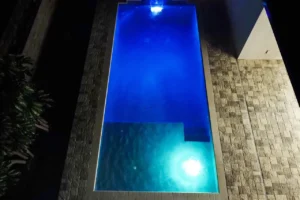 Custom pool at night with dark blue lighting | Winway Pools