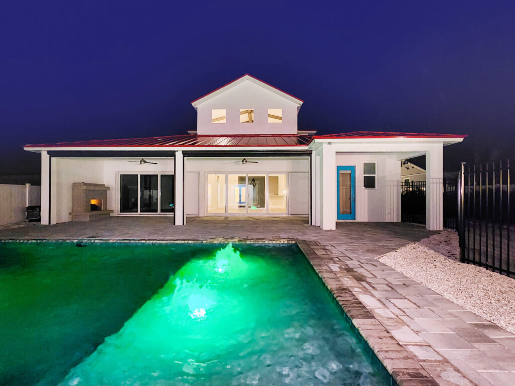 Picture of a custom home with a custom pool in the backyard at night | Winway Pools