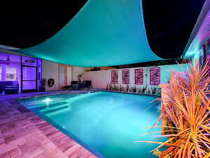 Custom Pool with canopy over it at night with and stone deck | Winway Pools