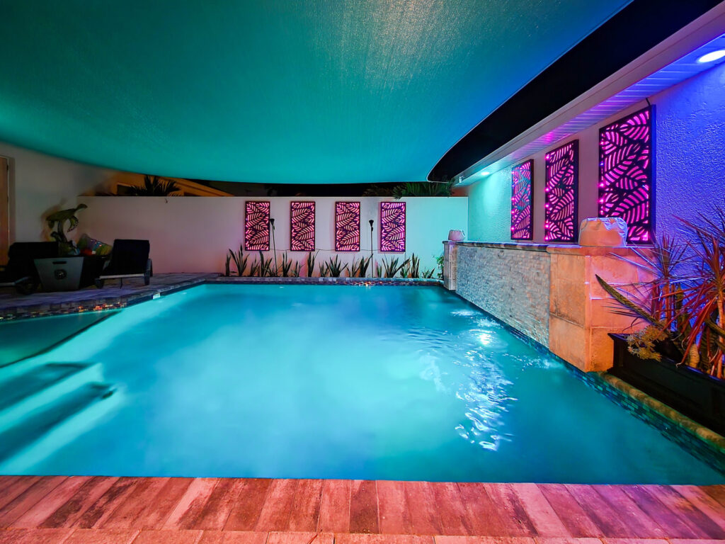 Custom indoor pool with stained glass, wood decking, and a water feature. | Winway Pools