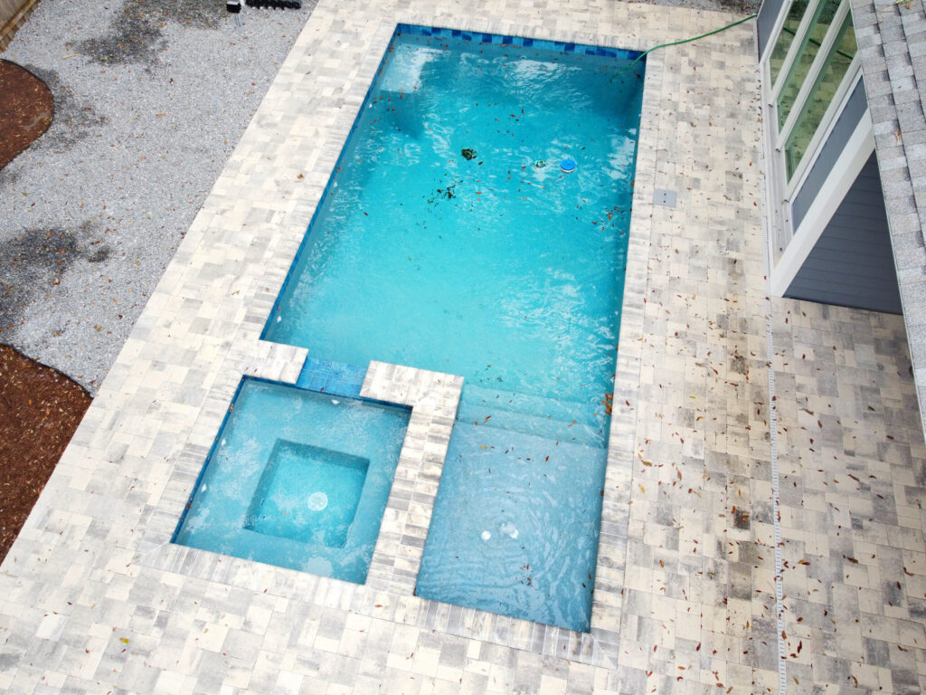 Aerial view of custom spa on a pool with mulch and gravel and a stone deck