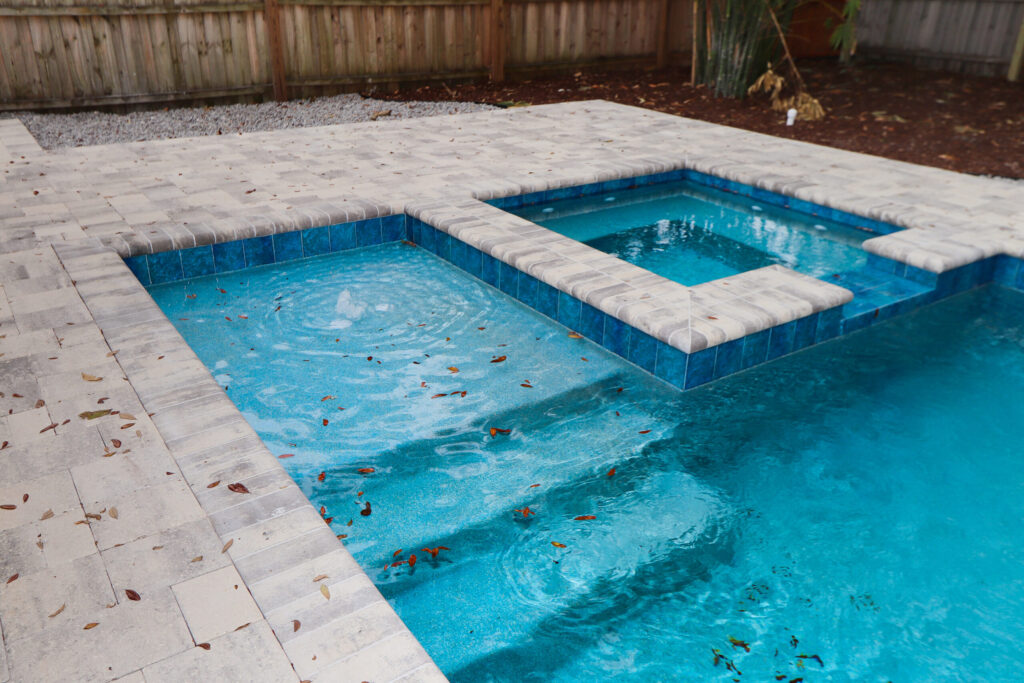 Custom spa on a pool with mulch and gravel surrounding a stone deck
