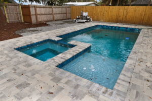 Custom spa on a pool with privacy fence surrounding a stone deck | Winway Pools