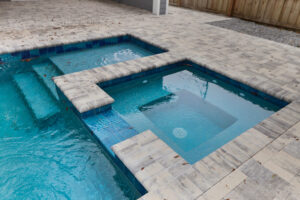 Custom spa attached to pool with stone decking | Winway Pools