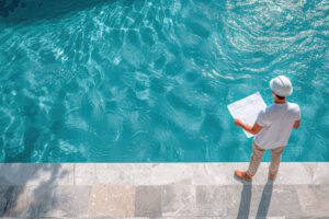 Engineer with a plan looking over a custom pool | Winway Pools