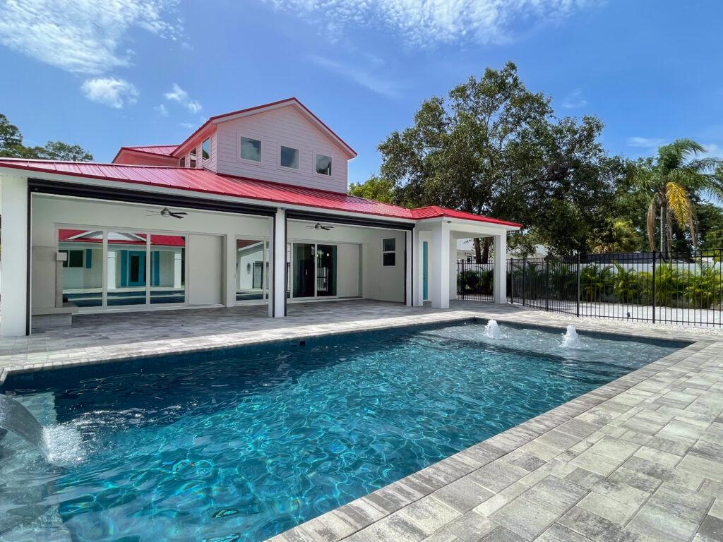 Custom pool with red-roof main house and gate | Winway Pools