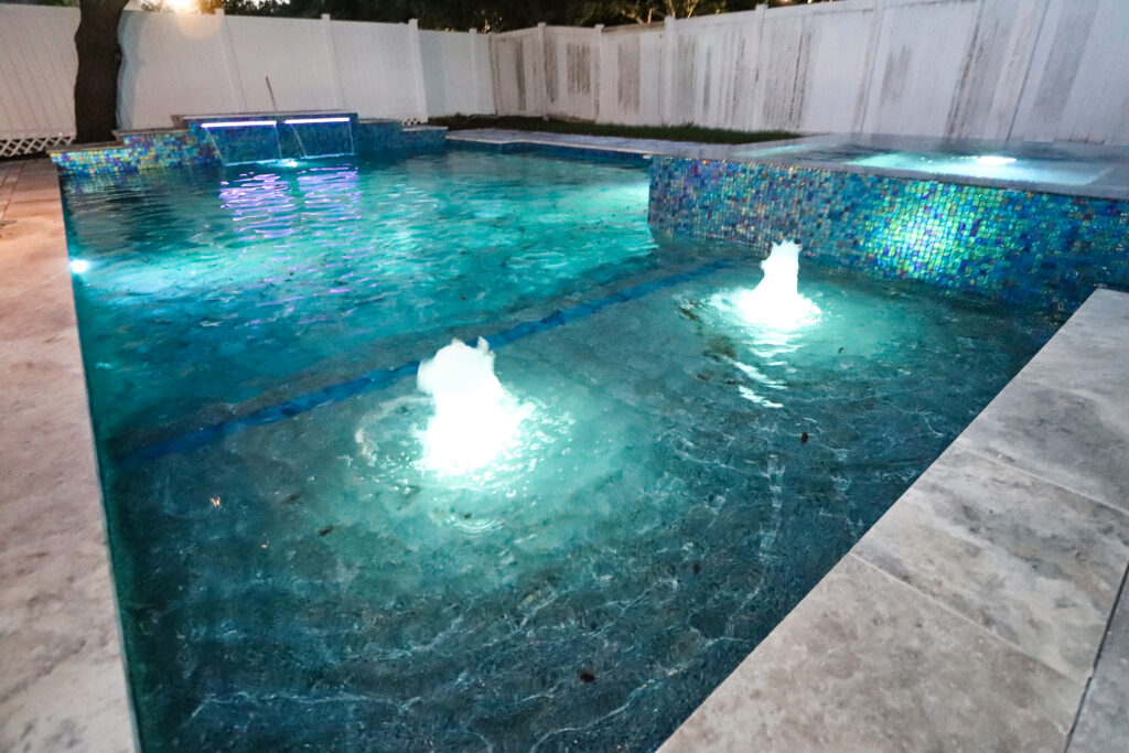 Custom pool nighttime fountains with lighting and waterfalls | Winway Pools