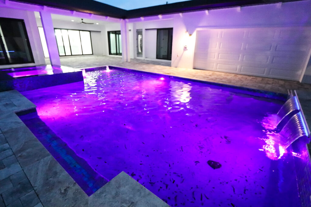 Custom pool nighttime with purple lighting | Winway Pools