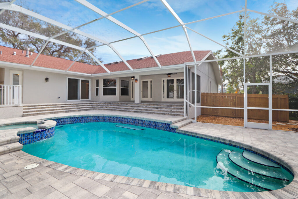 Custom pool under glass canopy behind house full view | Winway Pools