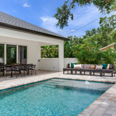 custom pool with pavers, patio, and a home in the background.
