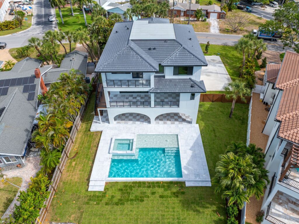Aerial view of luxury custom home with large backyard pool, spa, and spacious patio