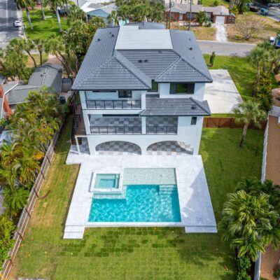 Aerial view of luxury custom home with large backyard pool, spa, and spacious patio