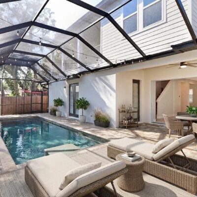 Screen-enclosed pool featuring a sun shelf, integrated spa, and covered patio seating