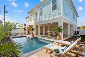 Custom swimming pool and covered outdoor living area beneath an elevated coastal home in Florida