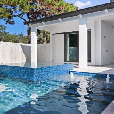 Luxury swimming pool with raised infinity-edge spa and water features beside a custom Florida home
