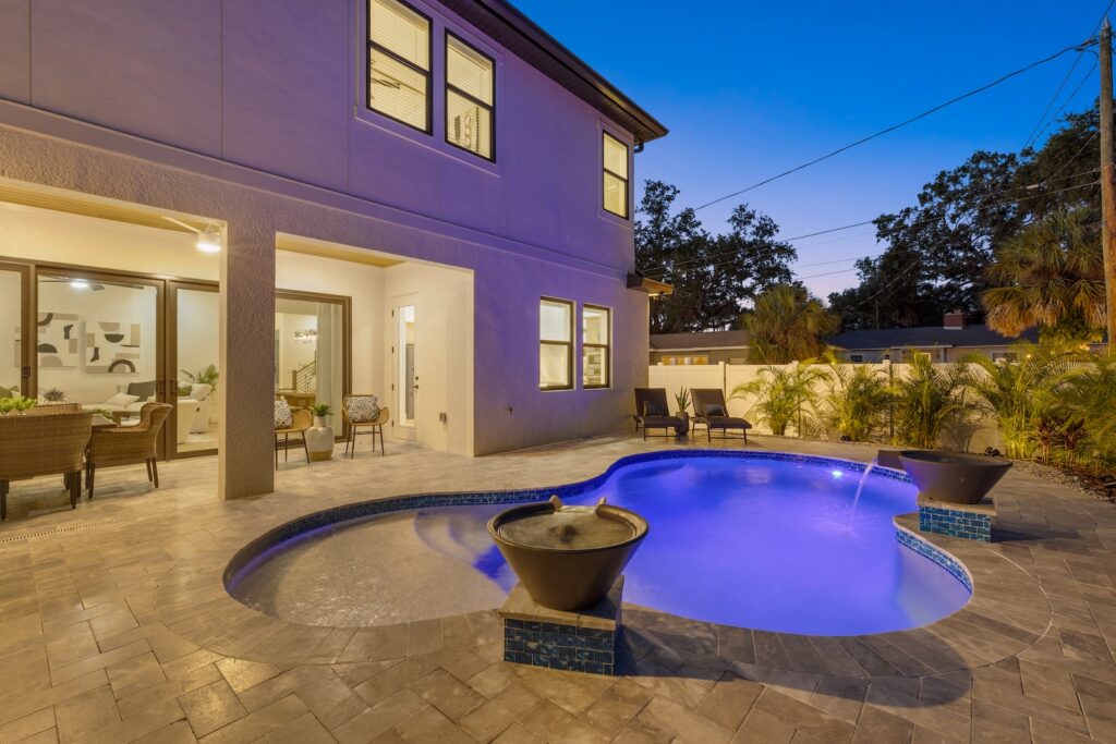 Stunning Outdoor Custom Pool at Twilight with Hardscape Framing Behind a New WinWay Home
